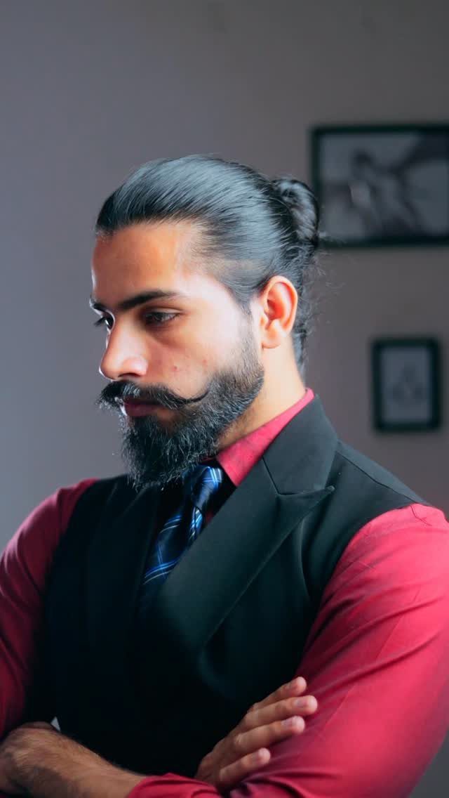 Man with a beard and a man bun wearing a formal vest.