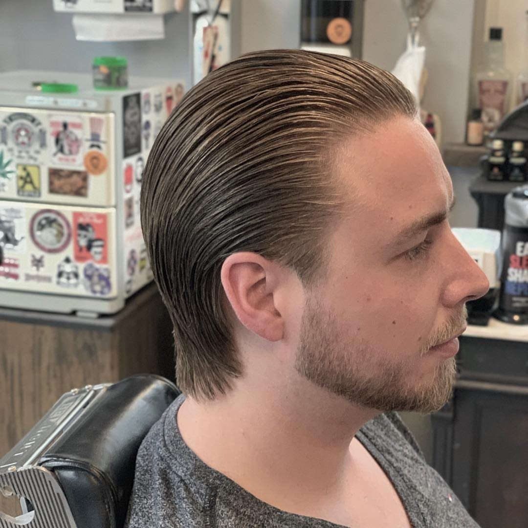 Man with brown hair combed back in a polished slick back hairstyle.