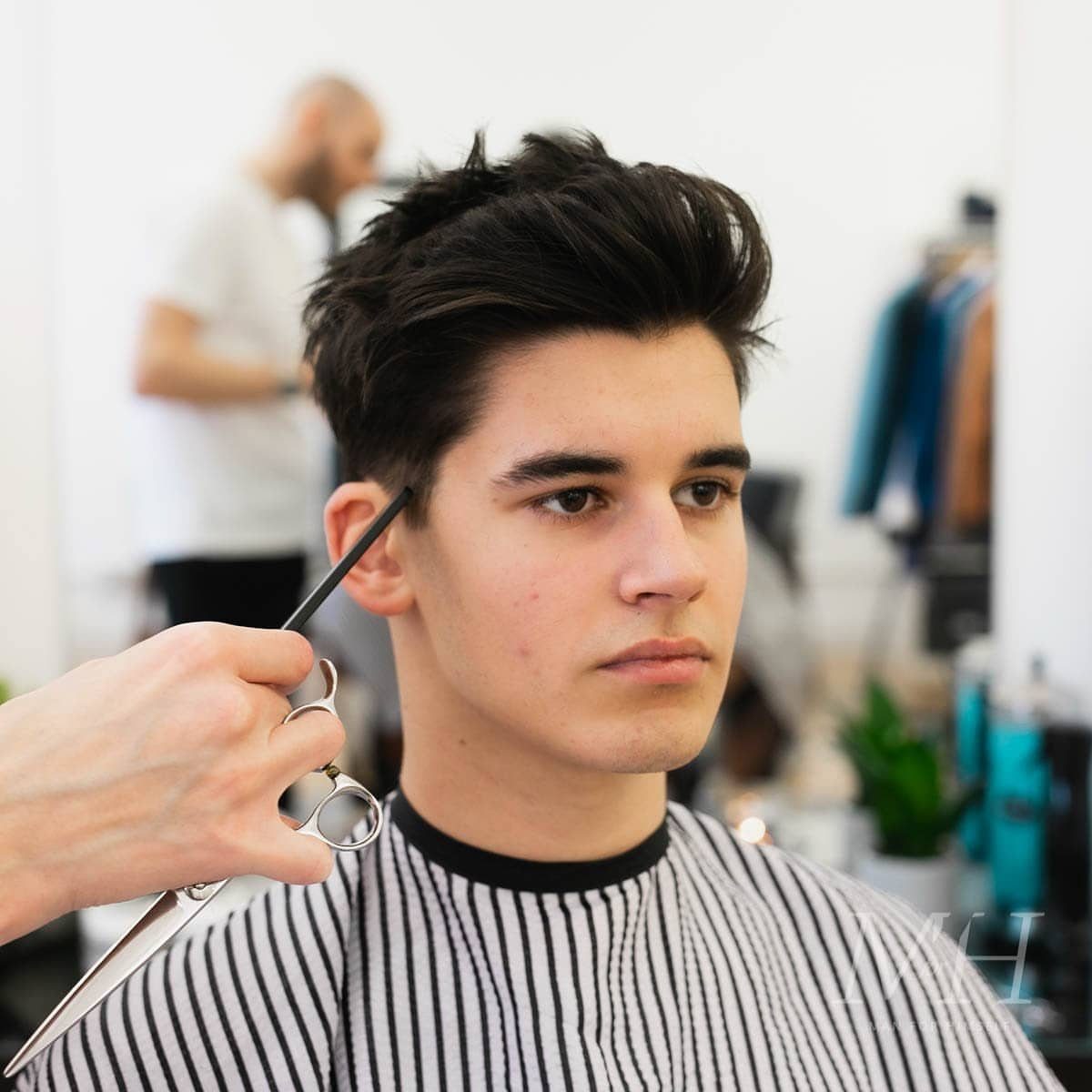 Young man with a textured quiff hairstyle getting a trim at a barbershop