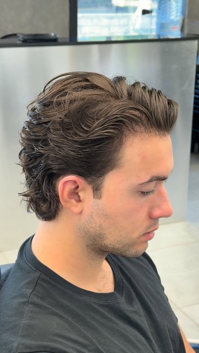 Man with medium-length wavy brown hair styled in a bro flow side profile.