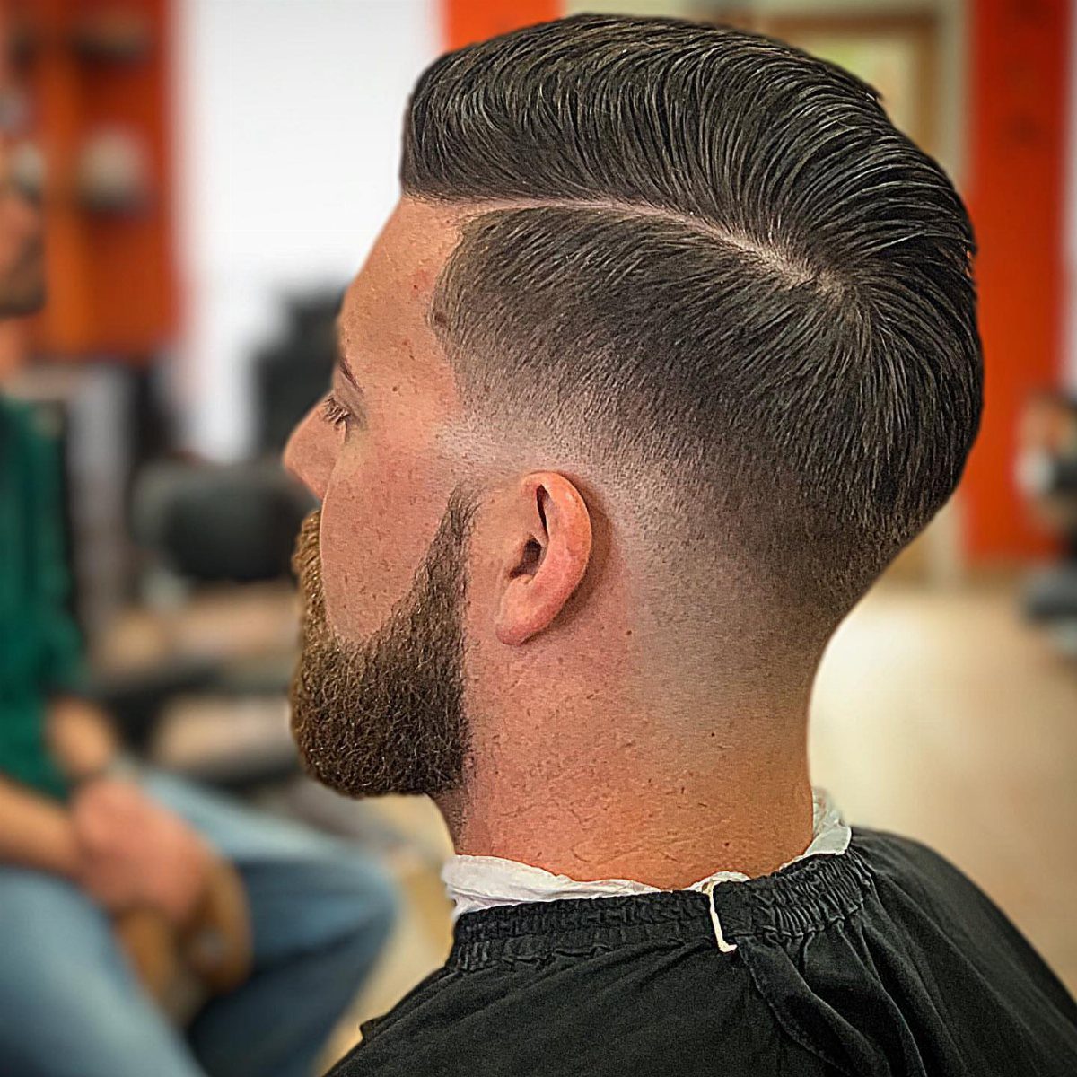 Man with a side-parted comb over hairstyle and a high skin fade haircut.