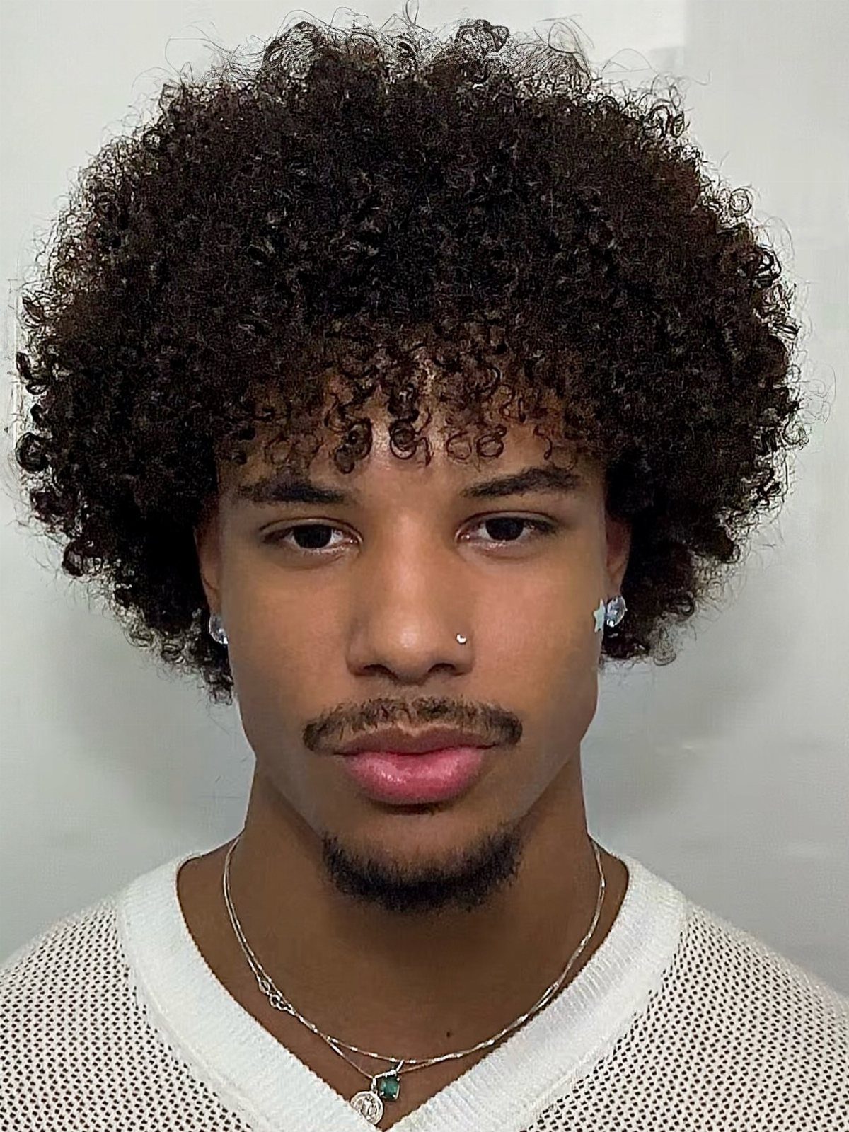 Man with a rounded medium-length afro, mustache, and goatee posing for a portrait.
