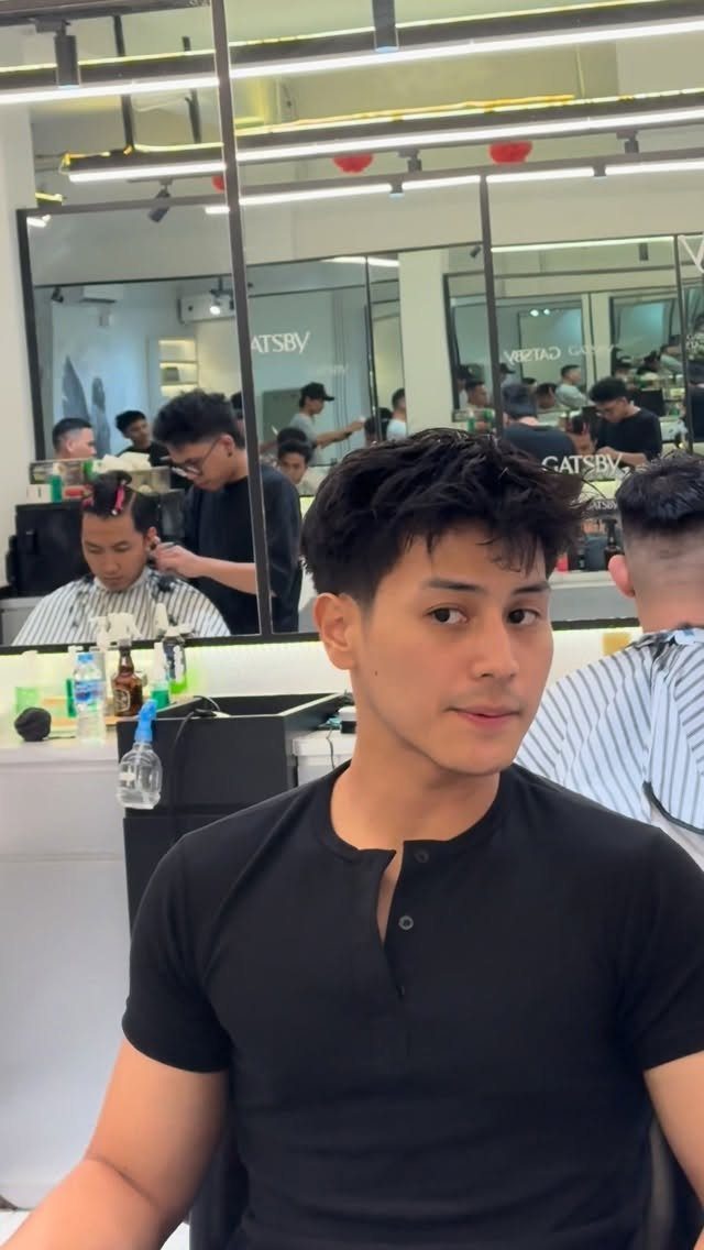 Man with dark medium-length hair and a textured fringe in a barbershop