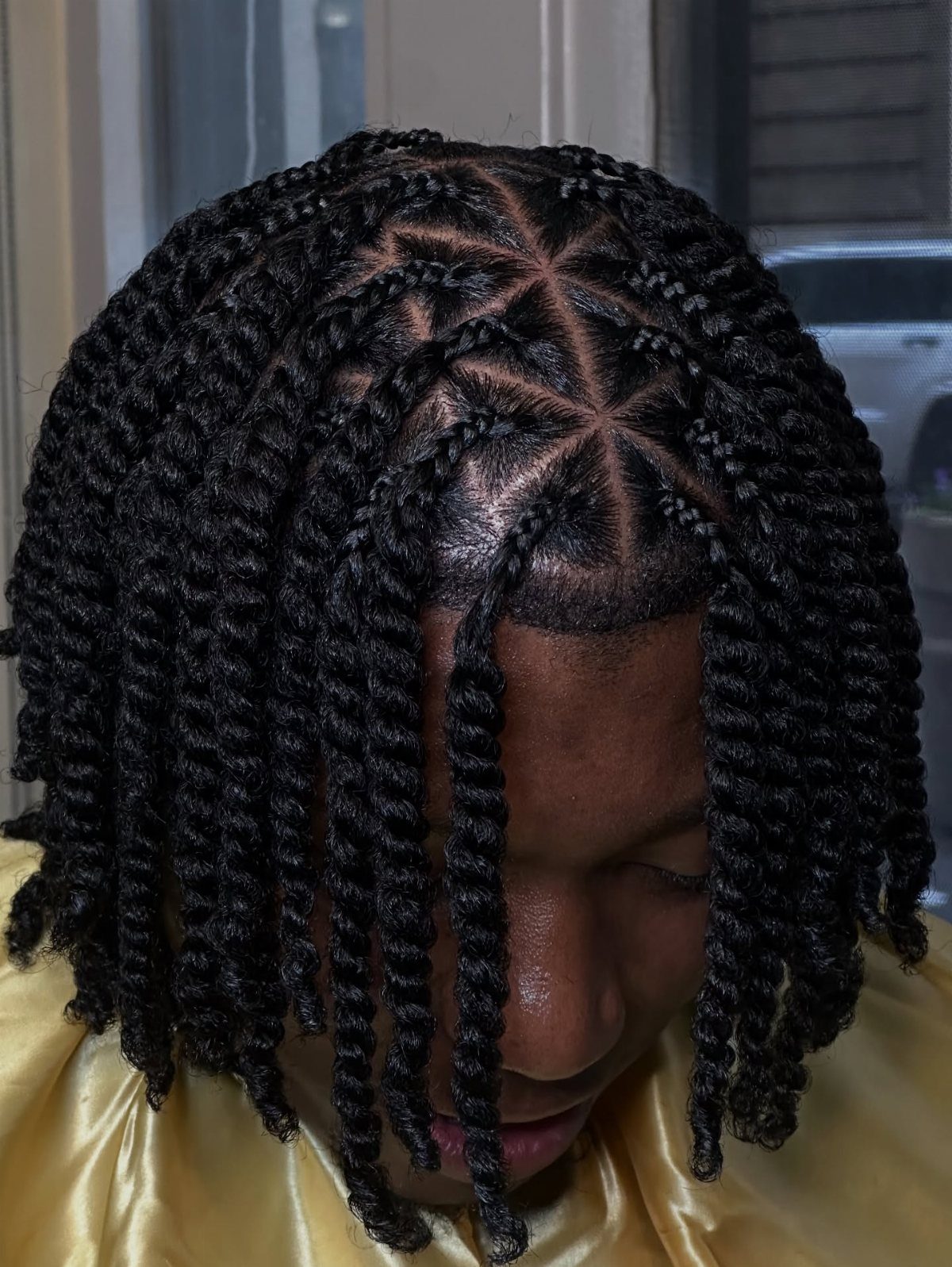 Man with medium-length black hair styled in neat individual twists and geometric parting.