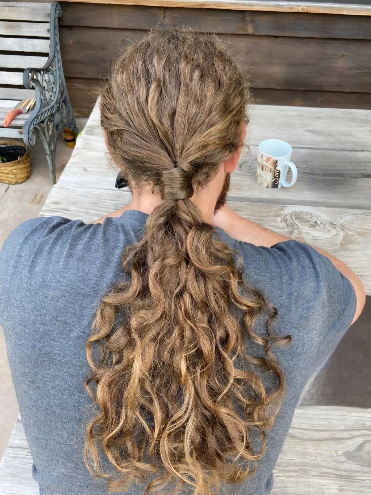 Long curly light-brown hair tied back into a ponytail from behind.