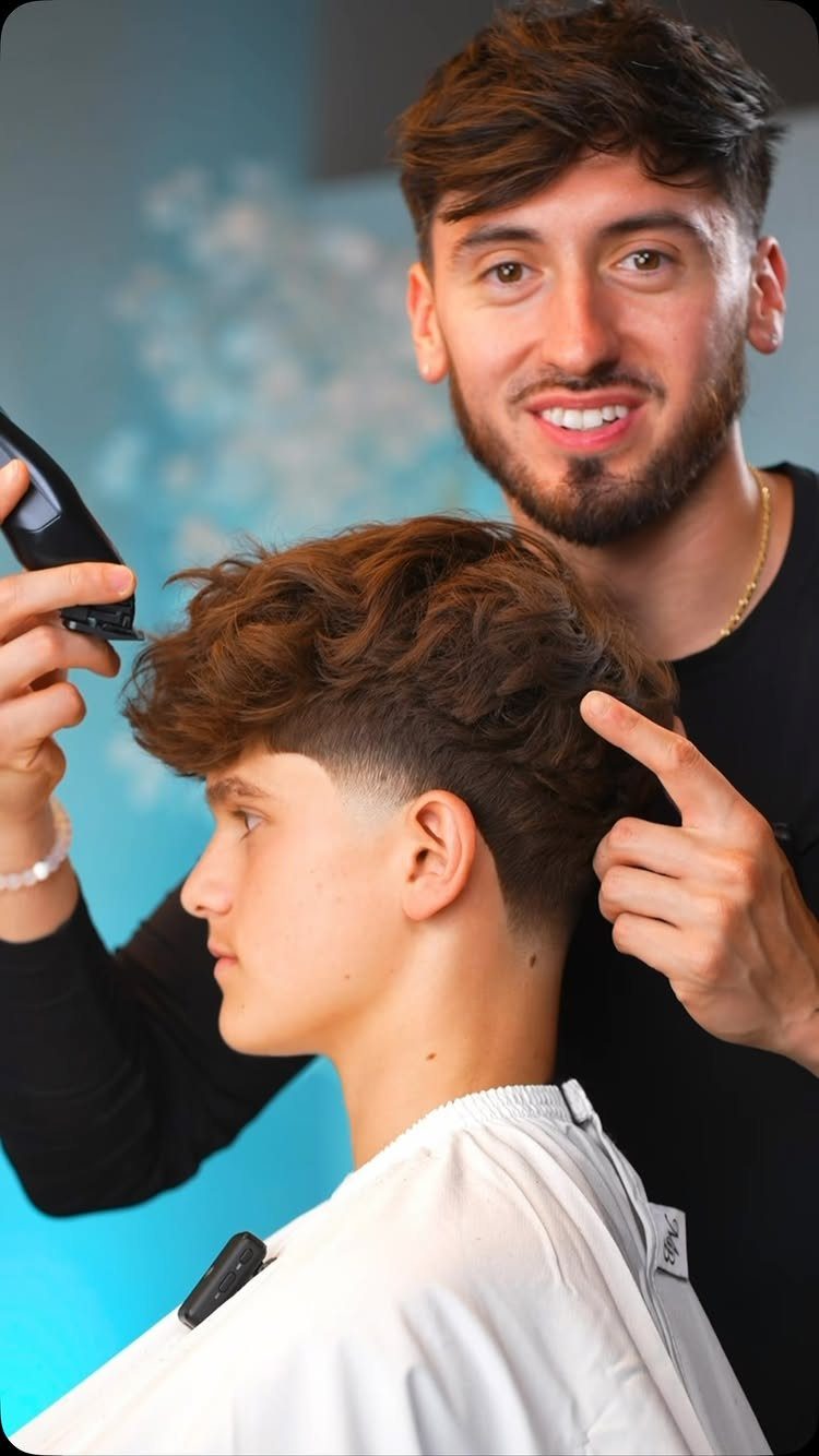 Barber pointing to a young man's brown medium-length taper haircut with textured top.