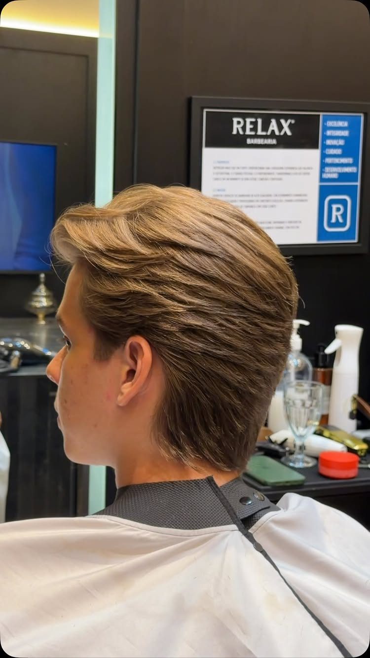 Young man with medium length swept-back light brown hair at a barbershop