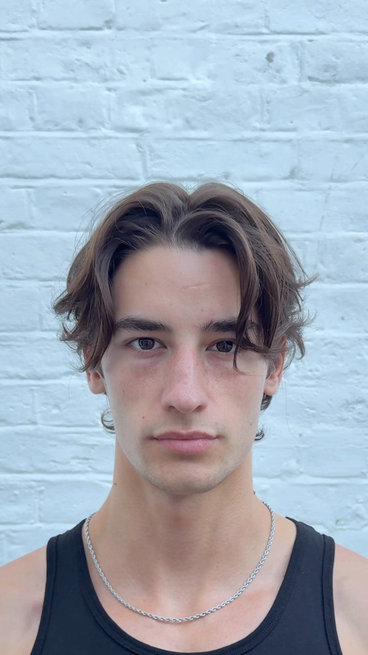 Young man with medium length straight brown hair parted in the middle