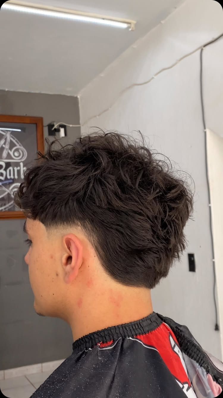 Man with thick textured wavy hair and a low skin fade haircut.