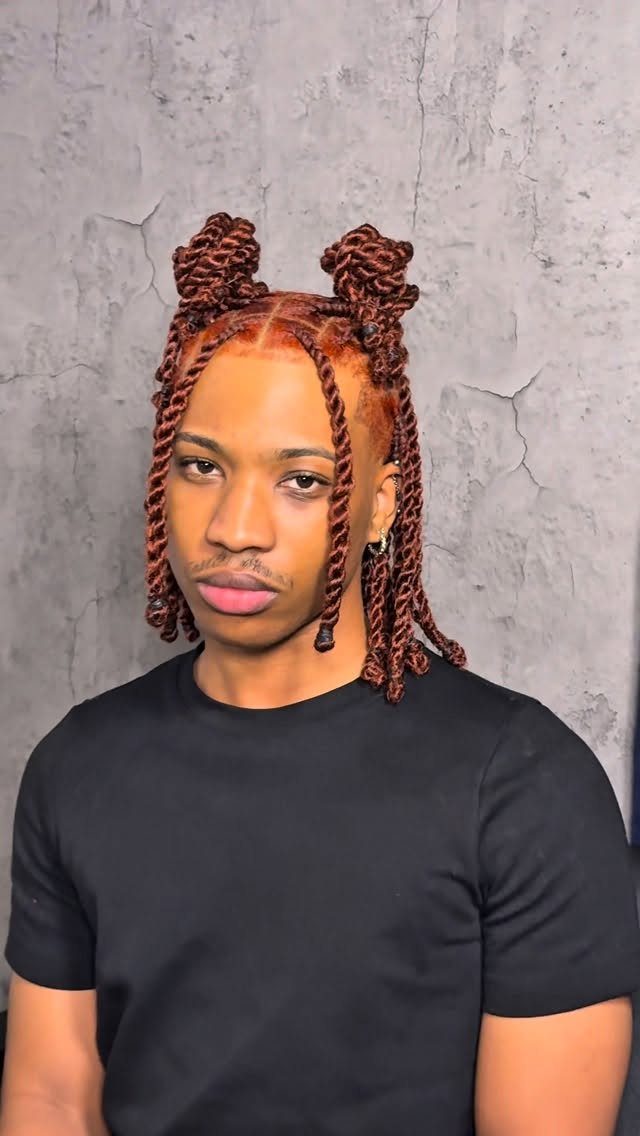 Man with reddish-brown twisted hair styled in two top buns and loose twists.