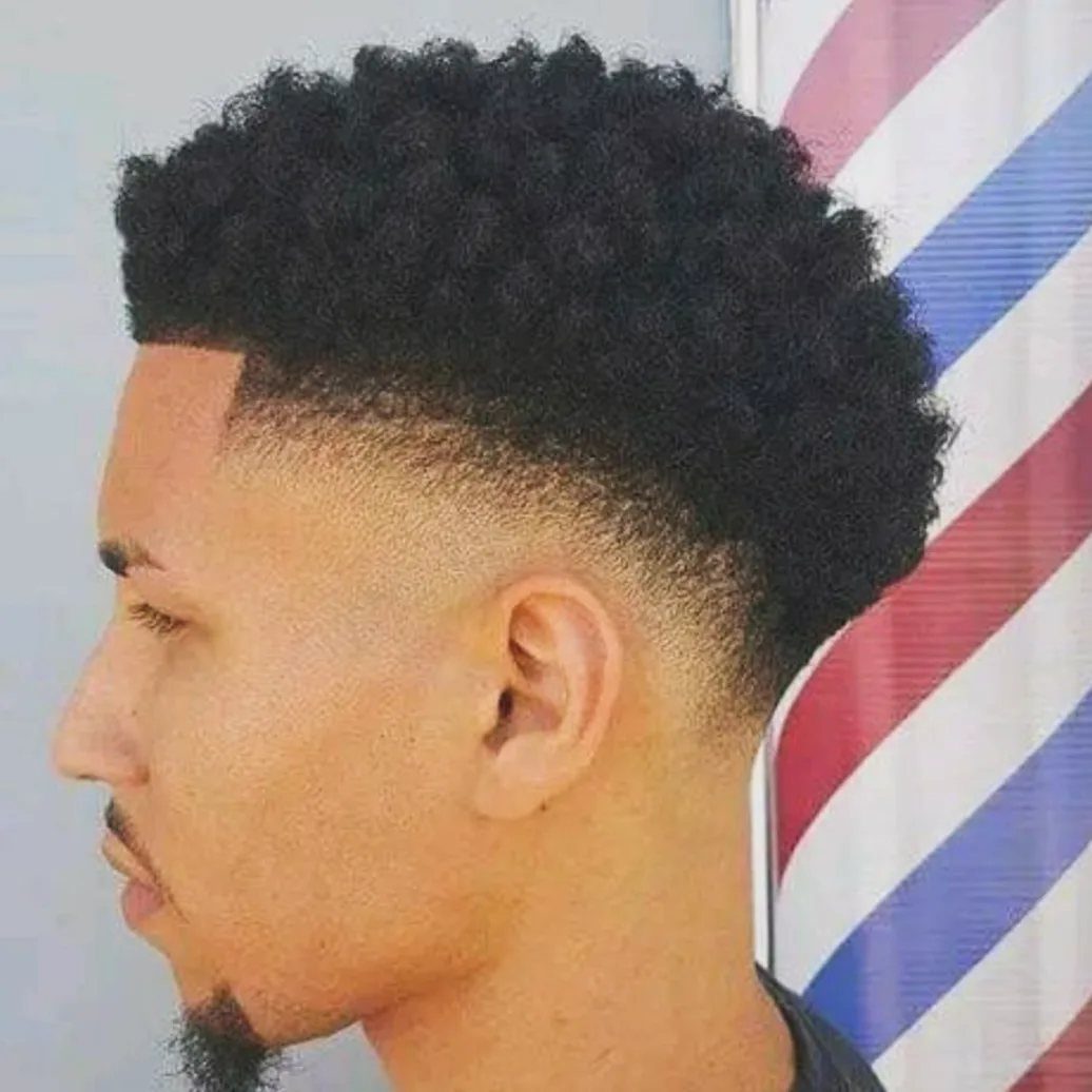 Man with a curly afro top and a clean mid skin fade haircut.