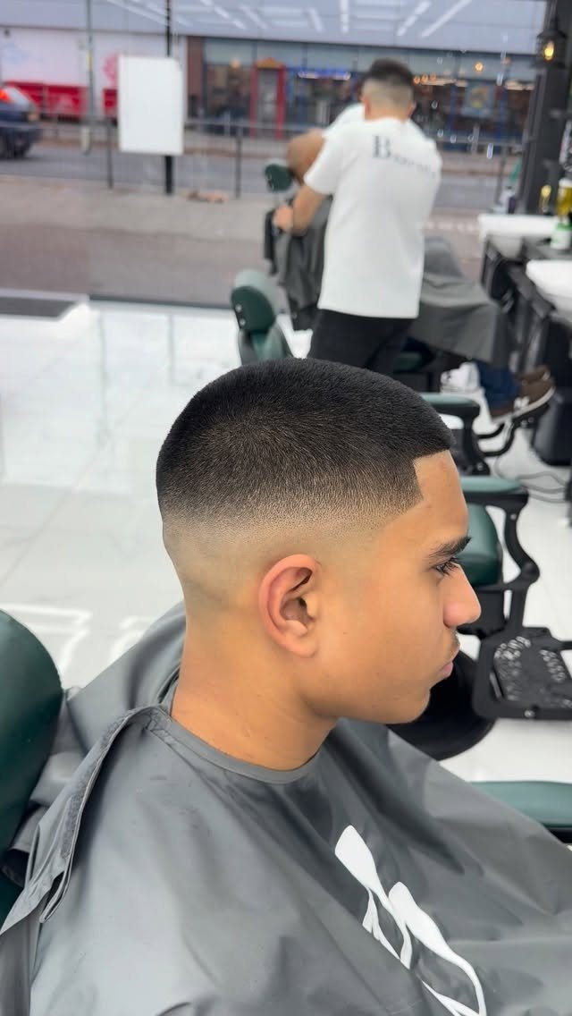 Young man with a short buzz cut and mid skin fade in barbershop