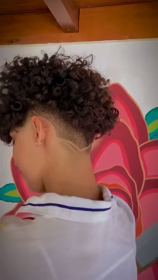 Person with curly hair on top and a faded haircut on the sides.