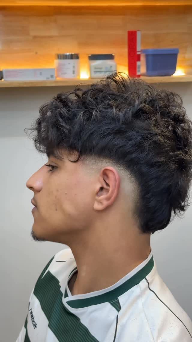Young man with curly dark hair and a mid fade haircut side profile