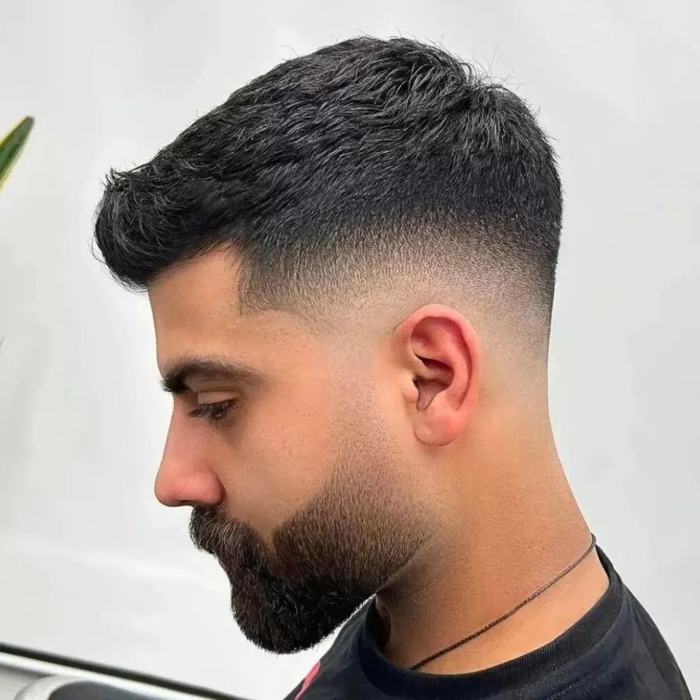 Man with a mid skin fade haircut and a styled brush up top.