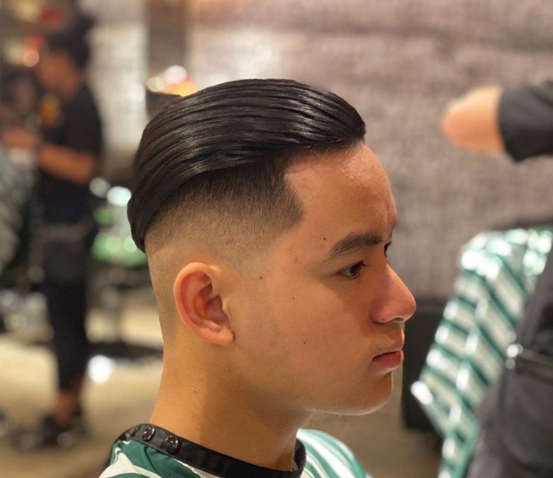 Man with a mid fade undercut and slicked back hair in a barbershop.