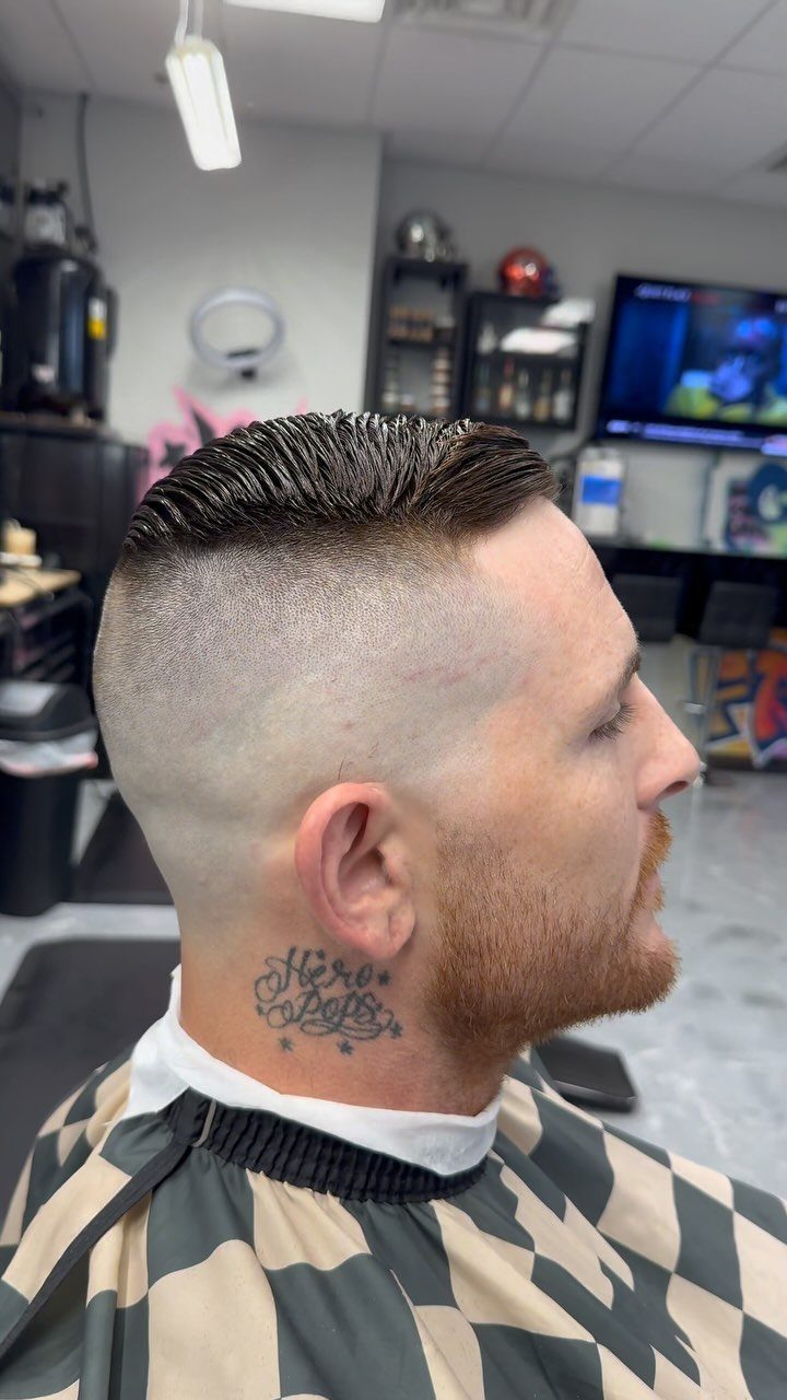 Man with a mid skin fade haircut and groomed beard in a barbershop.