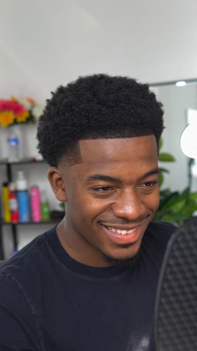 Man with a short afro top and a clean mid taper fade haircut.