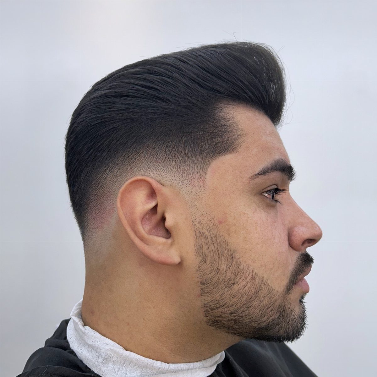 Man with a high volume pompadour haircut and a clean mid skin fade.