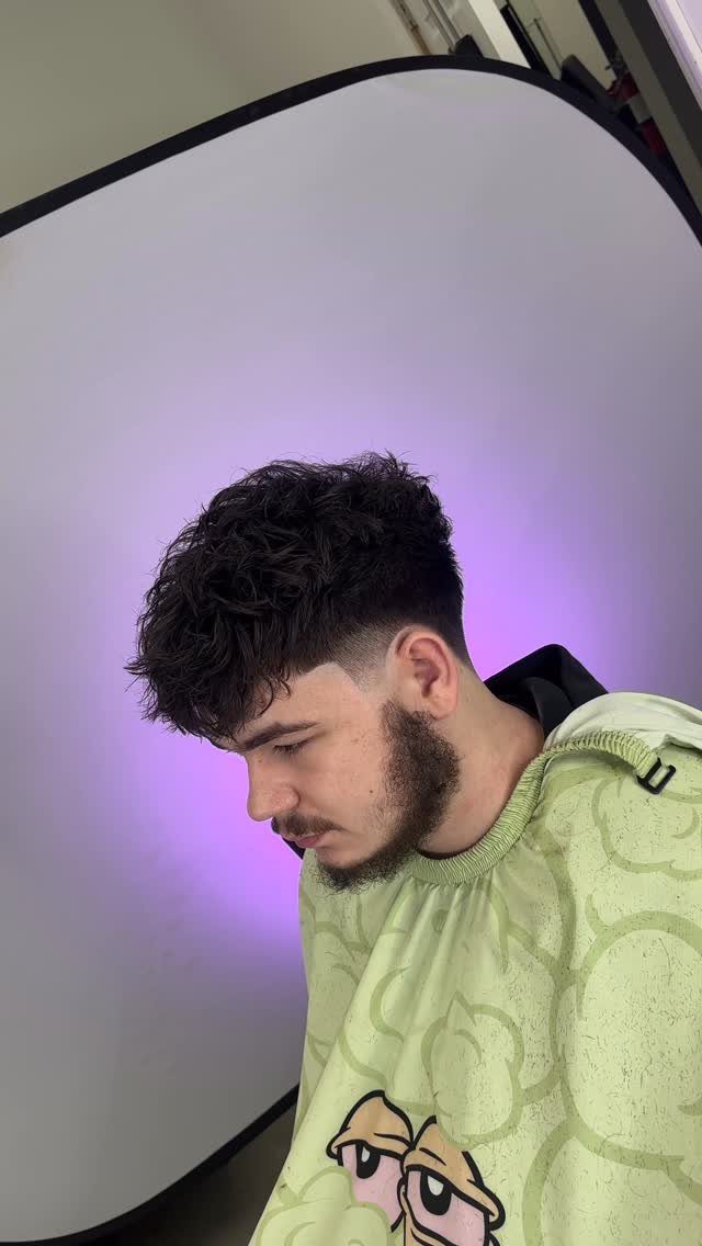 Young man with a textured fringe haircut and mid fade side profile.