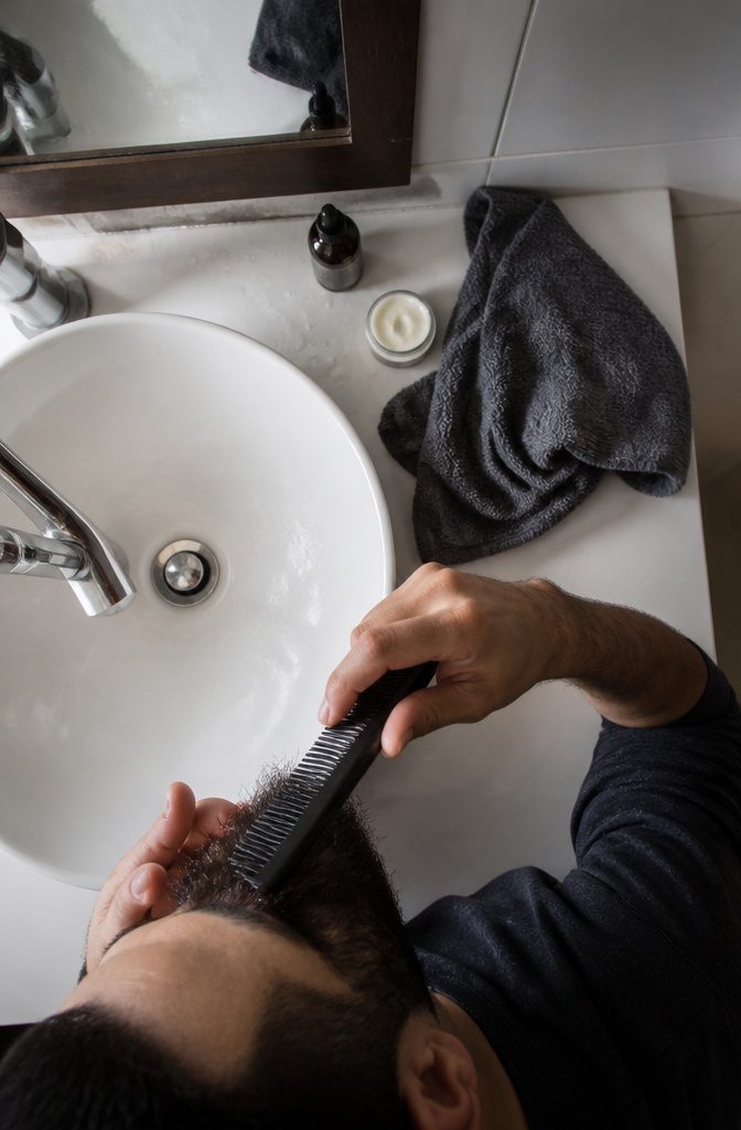 Hands applying beard oil through a slightly damp short beard