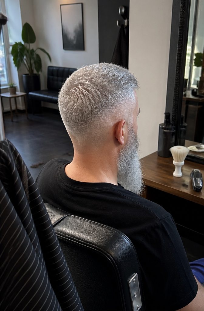 Man with short textured silver hair, tapered sides and a longer beard