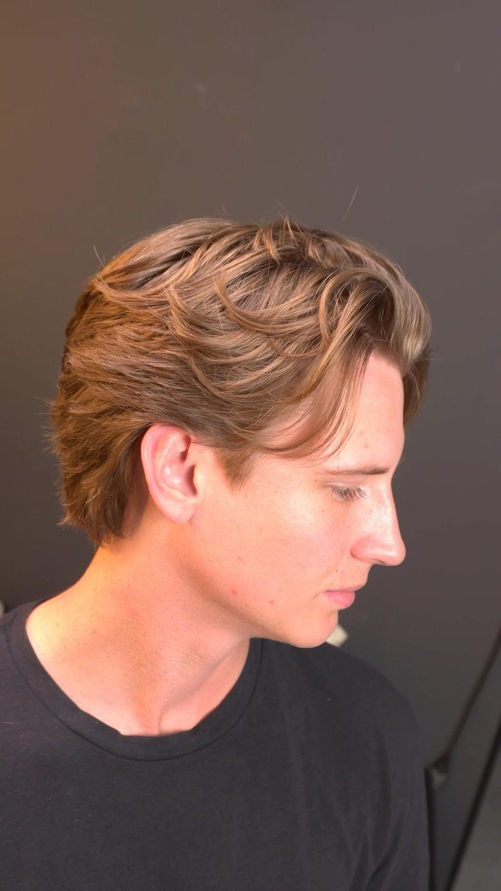 Young man with wavy brown hair styled in a voluminous bro flow hairstyle.