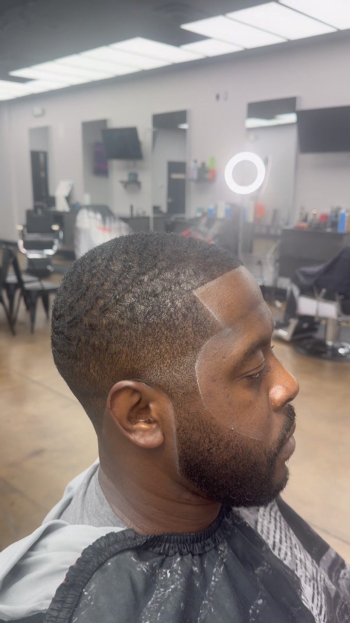 Man with a short buzzed haircut and sharp line up in a barbershop.