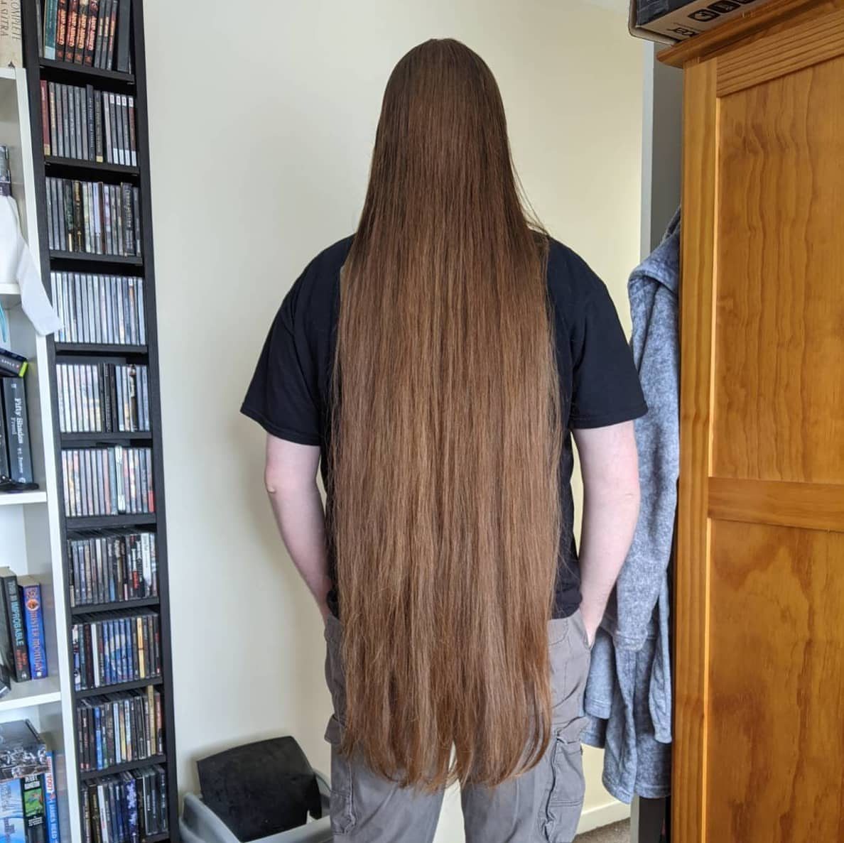 Person from behind with very long straight light brown hair reaching the thighs.