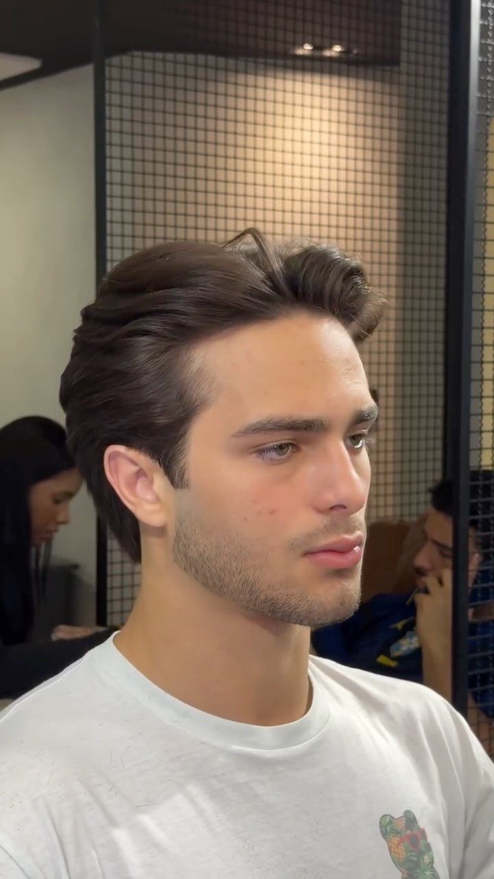 Young man with a brown quiff hairstyle and short sides in a barbershop.