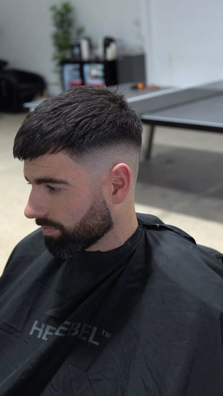 Man with a short crop haircut, skin fade, and a groomed dark beard.