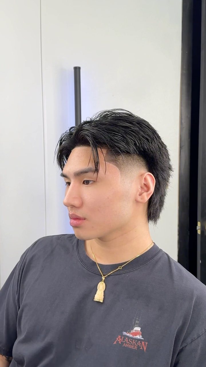 Young man with a straight black mullet haircut and shaved sides.