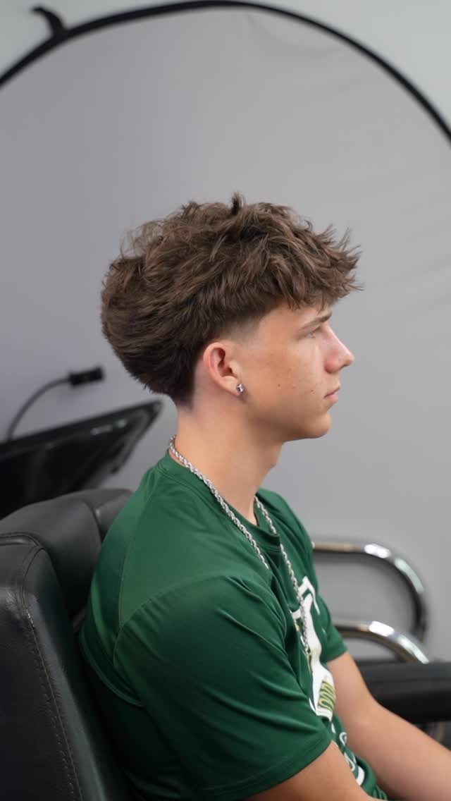 Young man with a textured crop haircut and forward fringe in a barber shop.