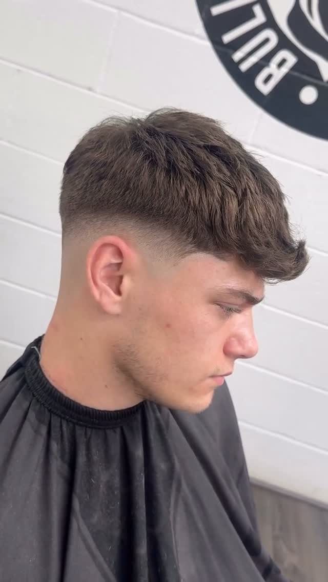 Young man with a low skin fade haircut and textured top in a barbershop.