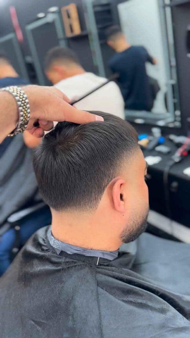 Man with a fresh skin fade haircut and groomed beard in a barber shop.