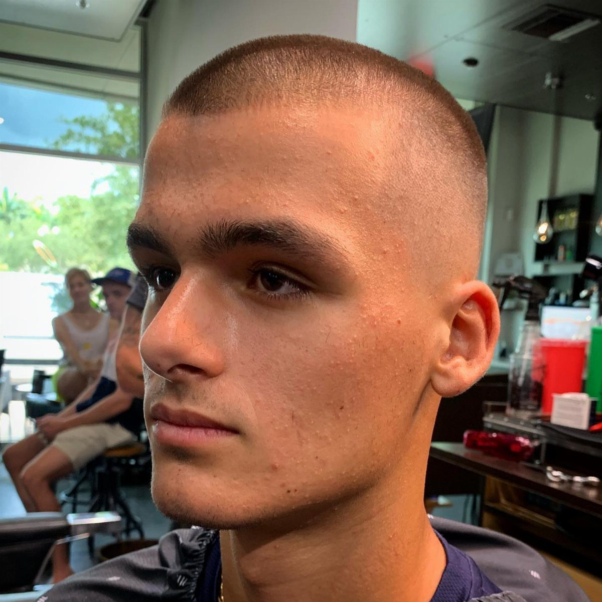 Young man with a skin-tight low fade buzz cut in a barbershop