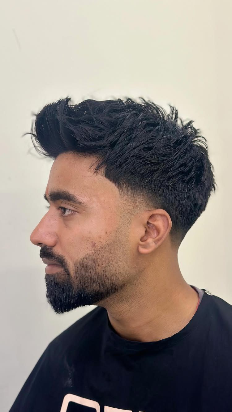 Man with a dark taper fade quiff haircut and a groomed beard.