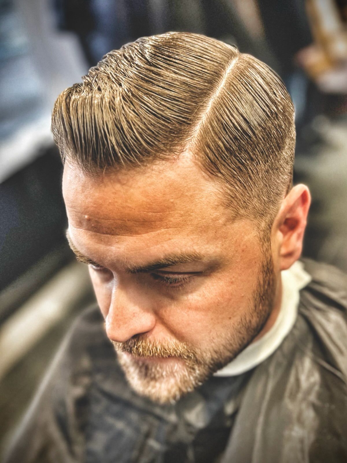 Man with a tapered hard part haircut and a groomed brown beard.