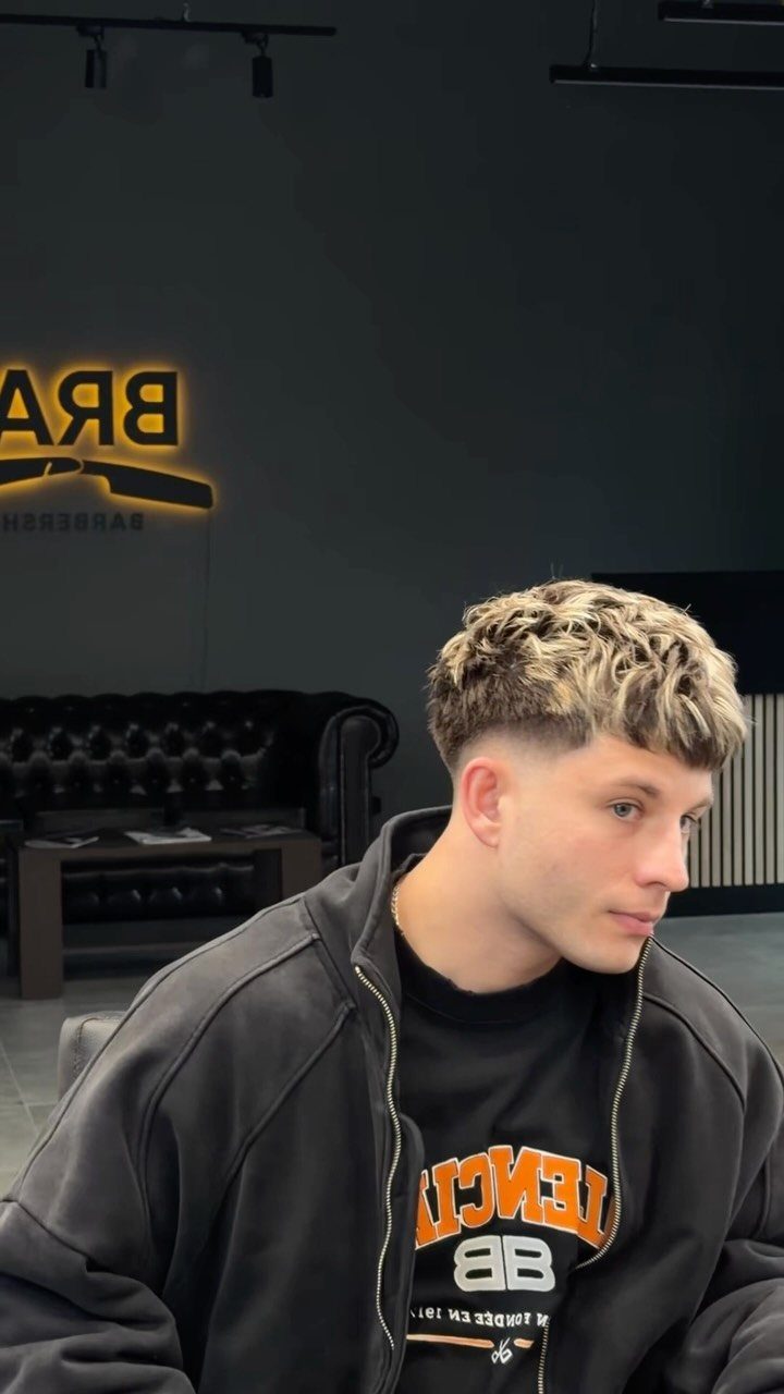 Young man with a blonde textured crop haircut and tapered sides in a barbershop.