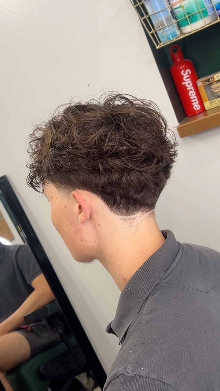 Man with curly textured hair and a low taper fade haircut side view