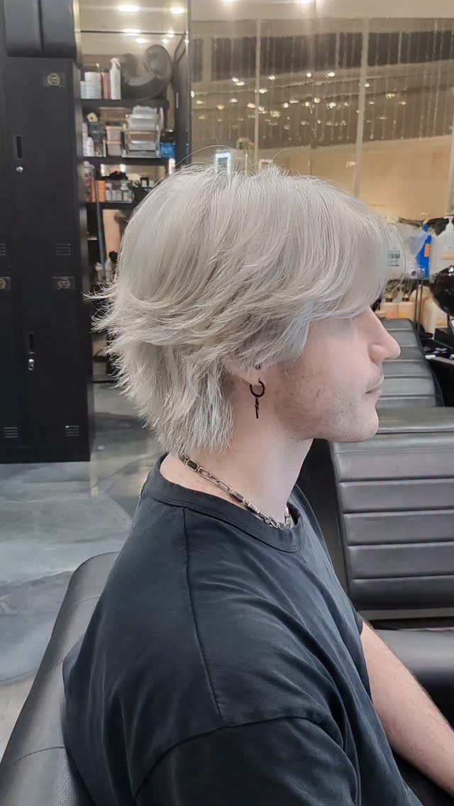 Man with a layered blonde wolf cut hairstyle posing in a hair salon.