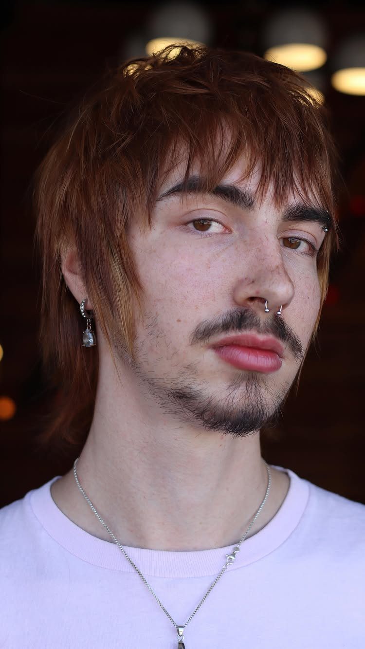 Man with reddish-brown layered wolf cut hair and bangs, wearing a purple shirt.