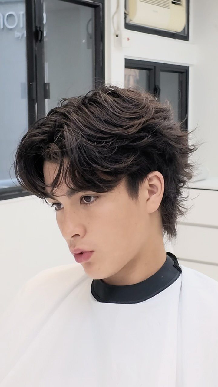 Man with a dark brown middle part wolf cut and voluminous layers.