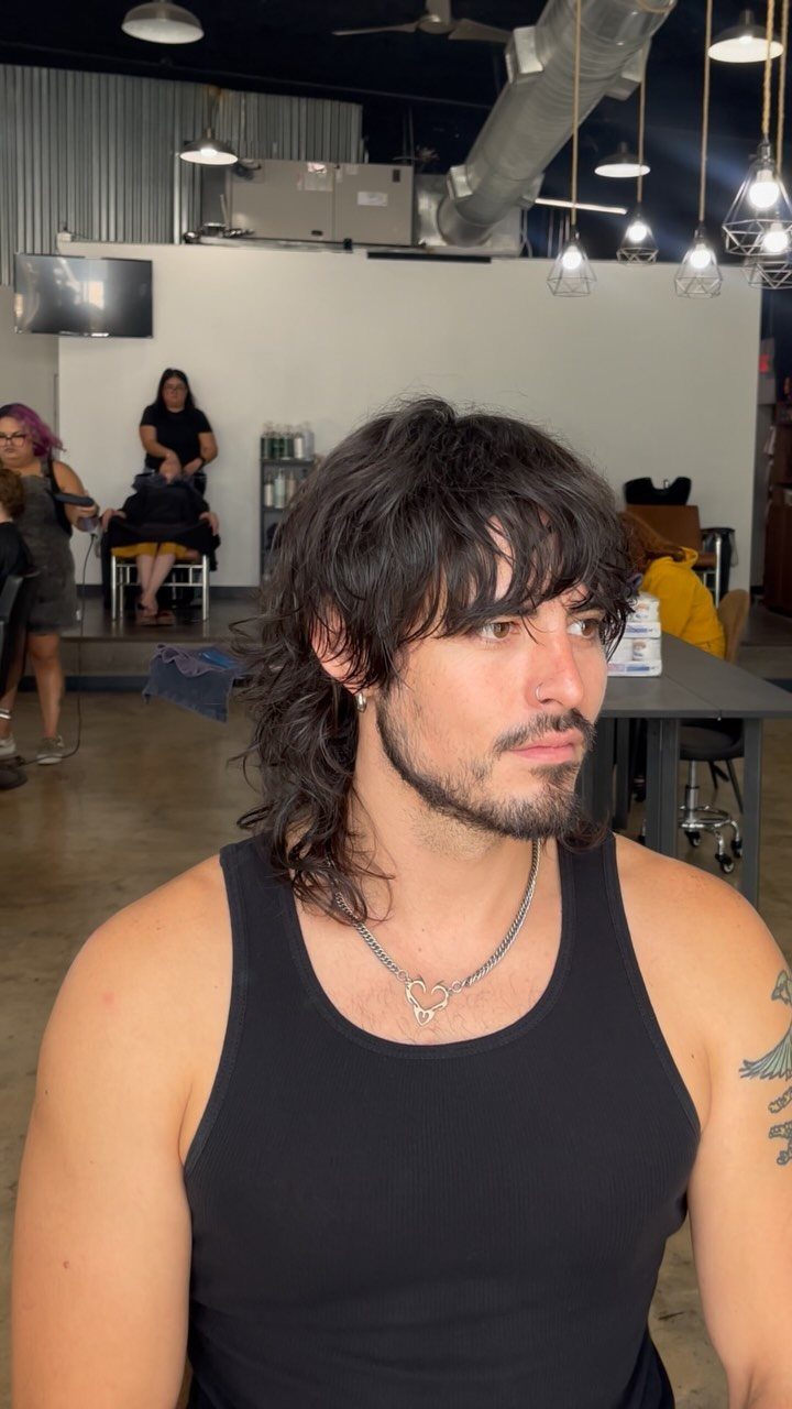 Man with a dark brown choppy layered wolf cut hairstyle in a salon.