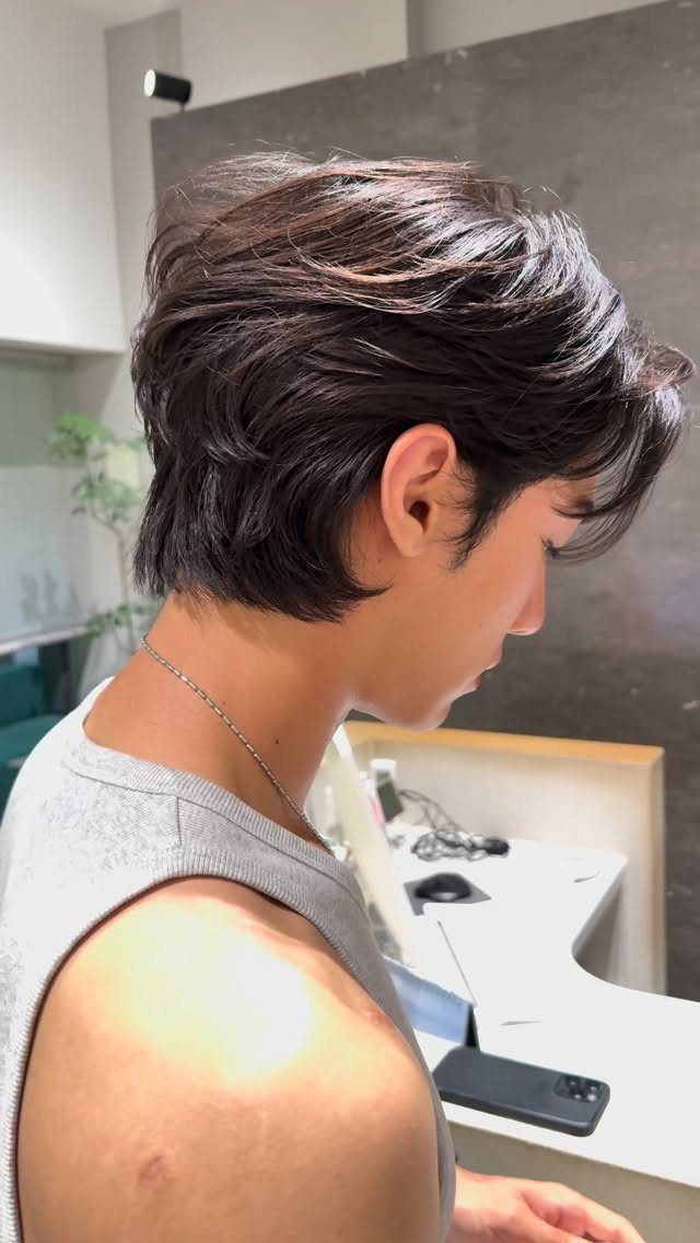 Young man with a soft-layered dark brown wolf cut hairstyle in side profile