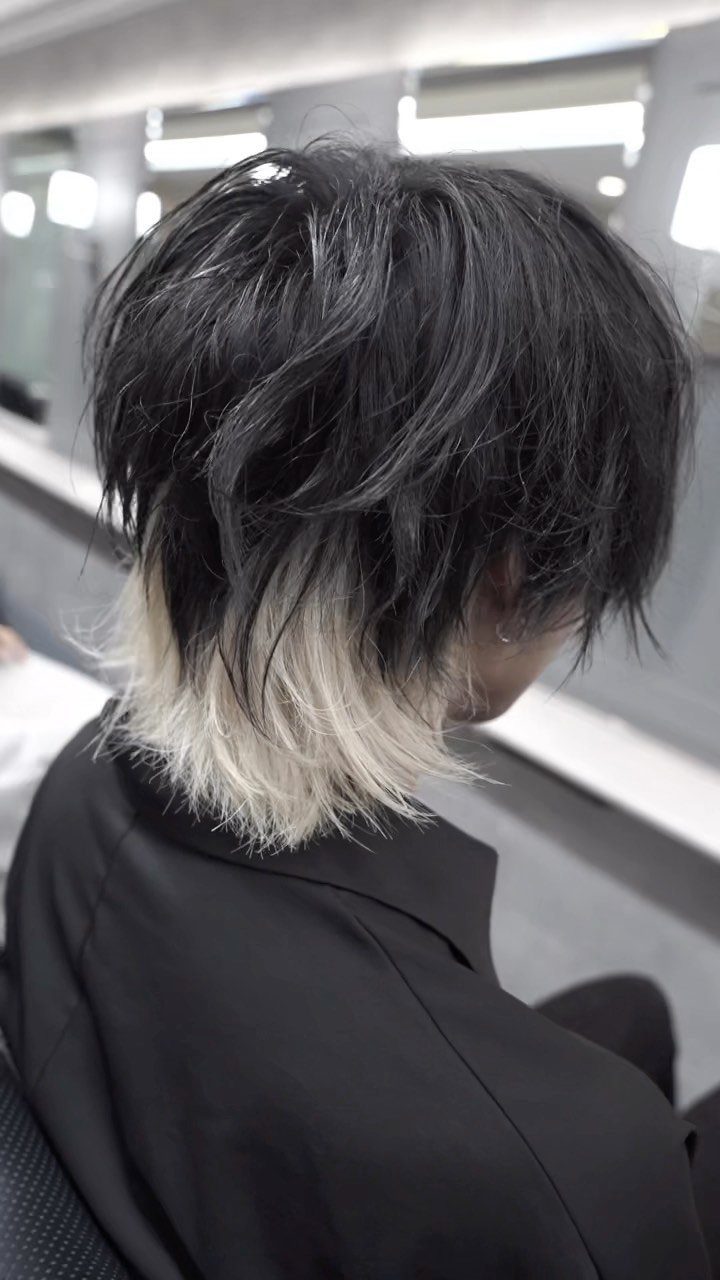 Man with a black and blonde layered wolf cut hairstyle wearing a black shirt.