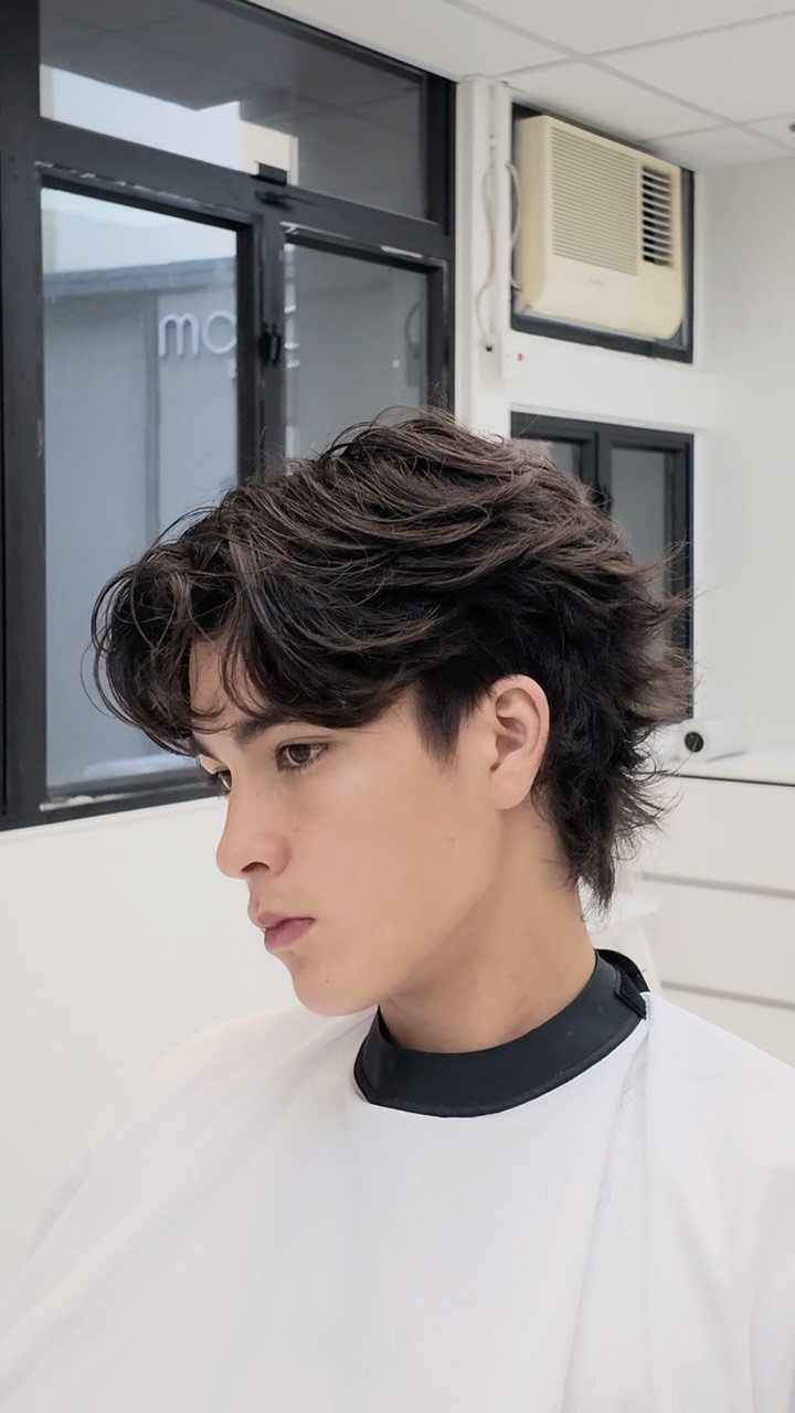 Man with a dark brown wispy layer wolf cut and voluminous crown.