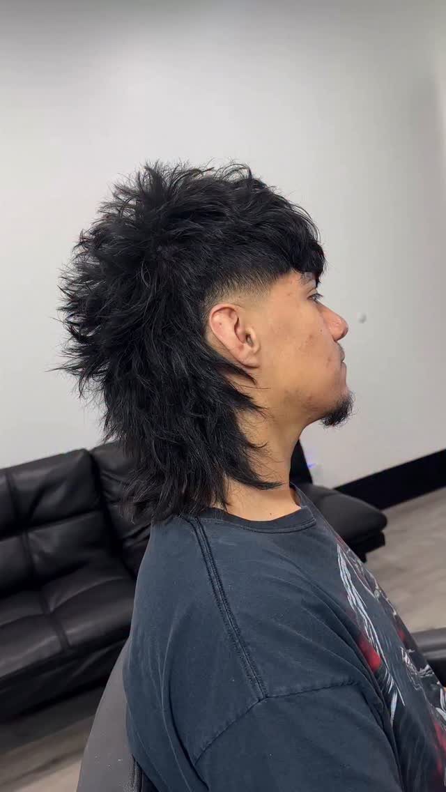 Man with a black wolf cut featuring a side fade and shaggy layers.